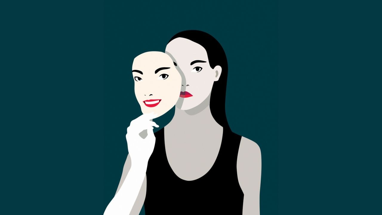 A woman holds a mask away from her face, where her face on the mask is smiling but the woman behind it is not.