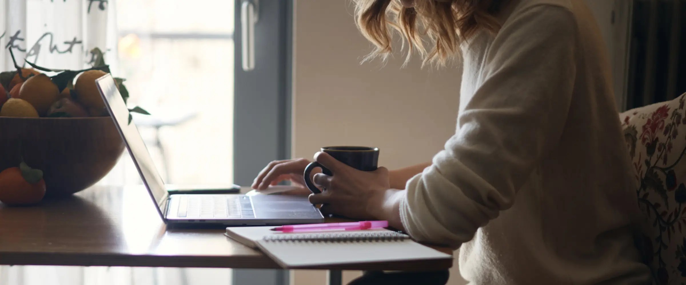 A writer working on their laptop at the kitchen table.